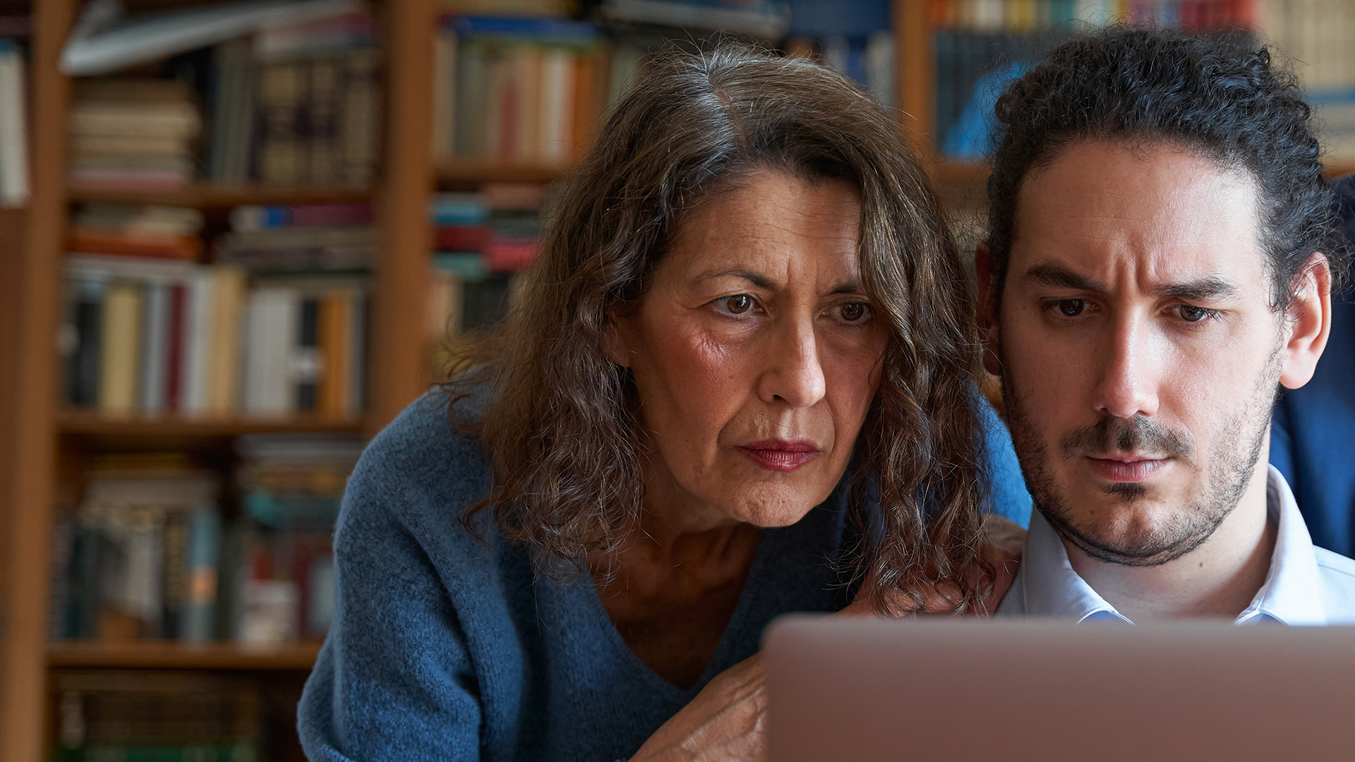 Mutter mit erwachsenem Sohn vor Laptop mit verzweifeltem Gesichtsausdruck